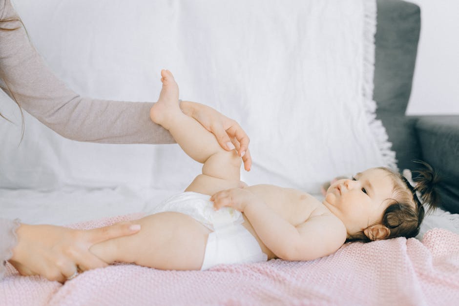 Mother gently massaging newborn baby on a soft surface